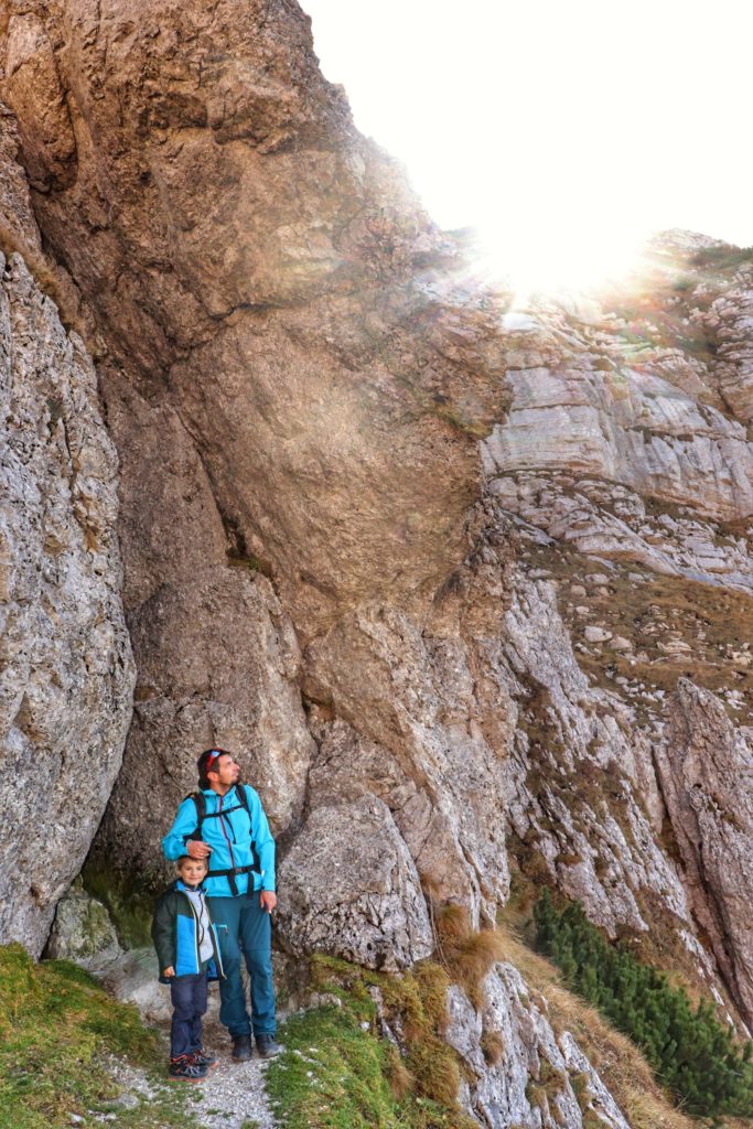 Dziecko wraz ojcem pod wysokimi skałami w Tatrach, słońce oświetlające wierzchołki skał