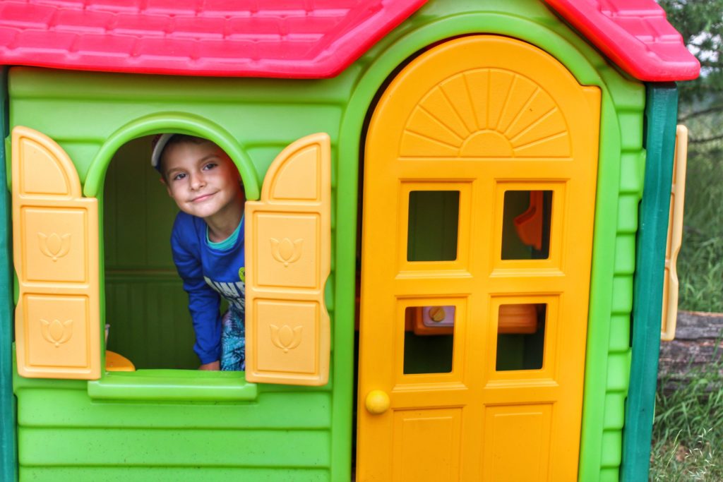 chłopiec w plastikowym, kolorowym domku na Trzech Kopcach, wychylający z okienka 