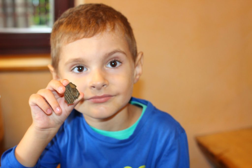 dziecko trzymające w rączce metalową odznakę turystyczną schroniska na Trzech Kopcach Wiślańskich