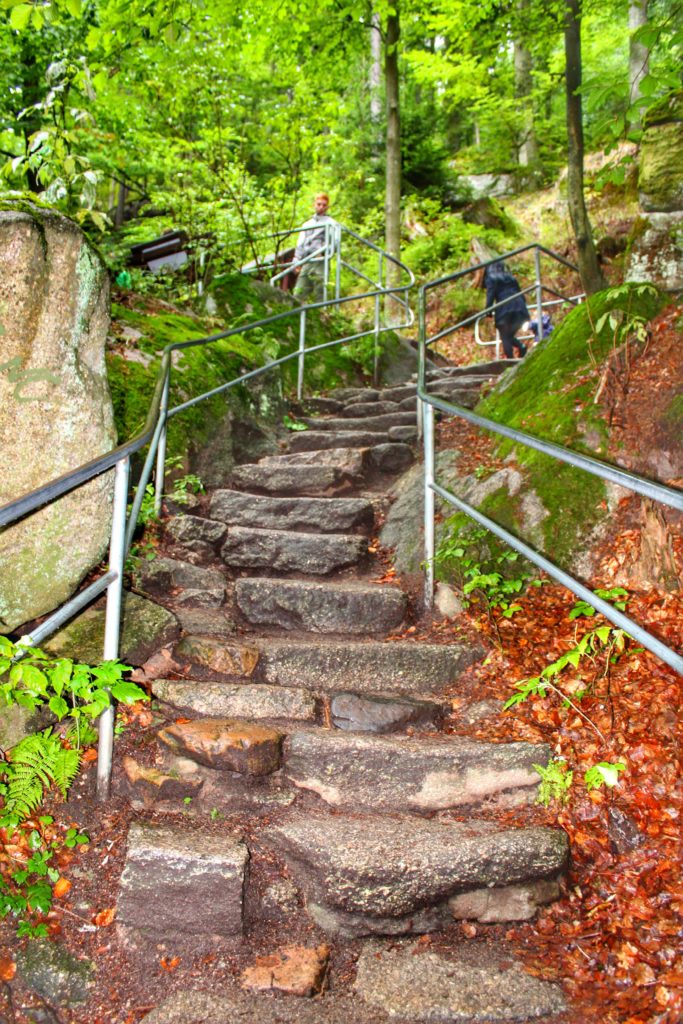 kamienne schody w lesie prowadzące niebieskim szlakiem od Wodospadu szklarki, w tle turyści
