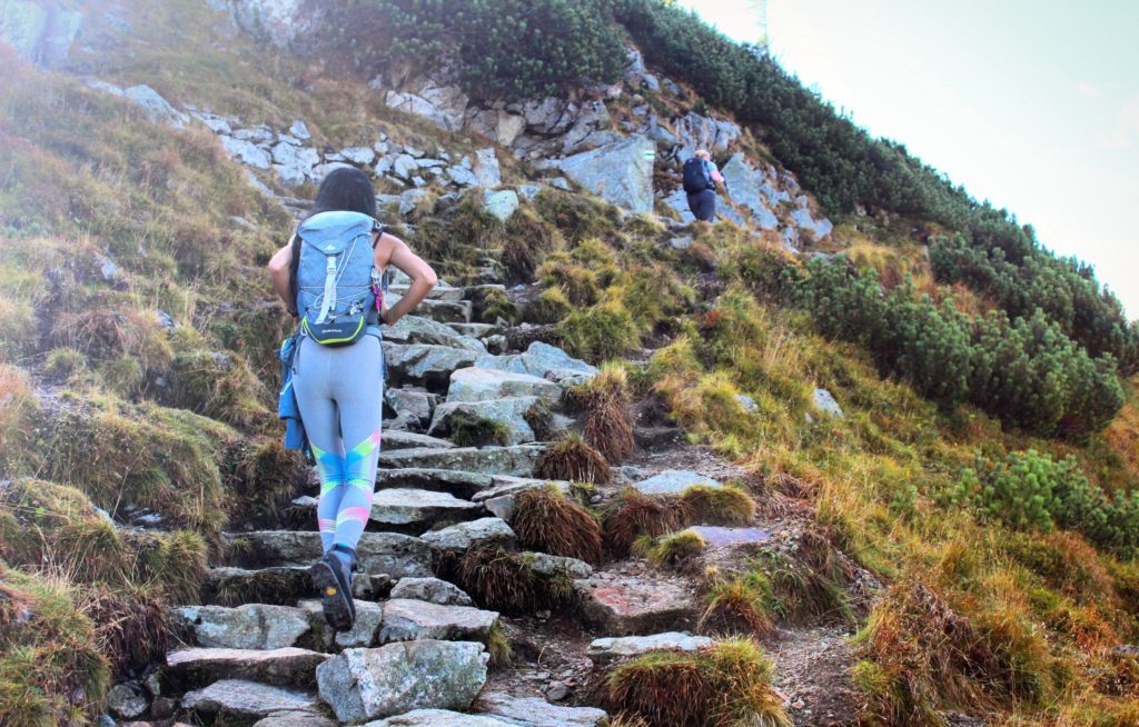 kobieta idąca po skalnych schodach zielonym szlakiem na Kasprowy Wierch
