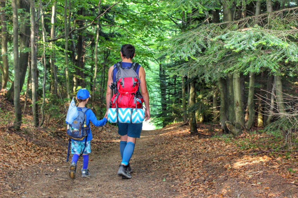 mężczyzna idący z dzieckiem przez las