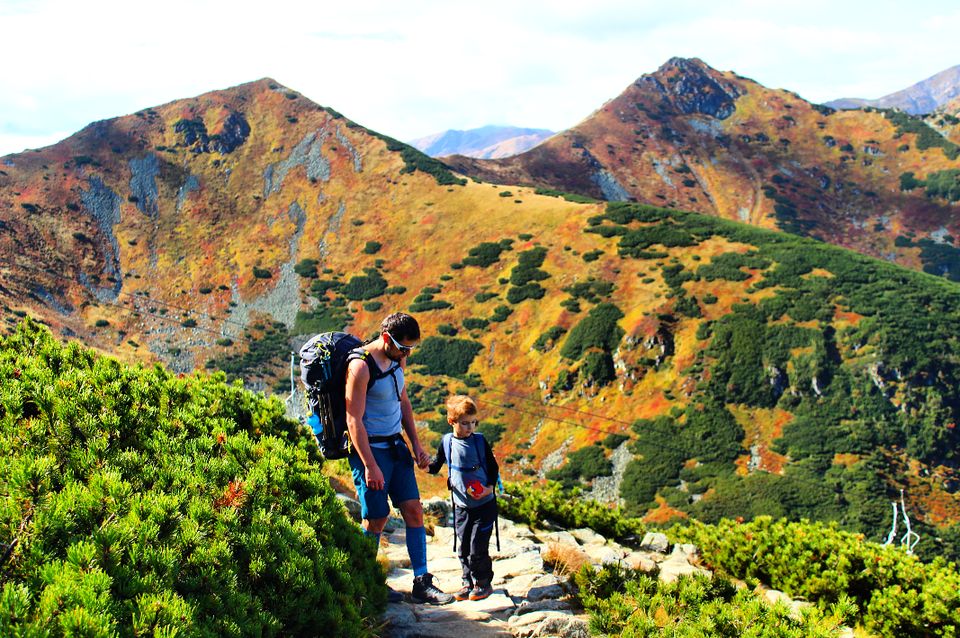 mężczyzna z dzieckiem stojący na tle natrzańskich szczytów pokrytych jesiennymi barwami