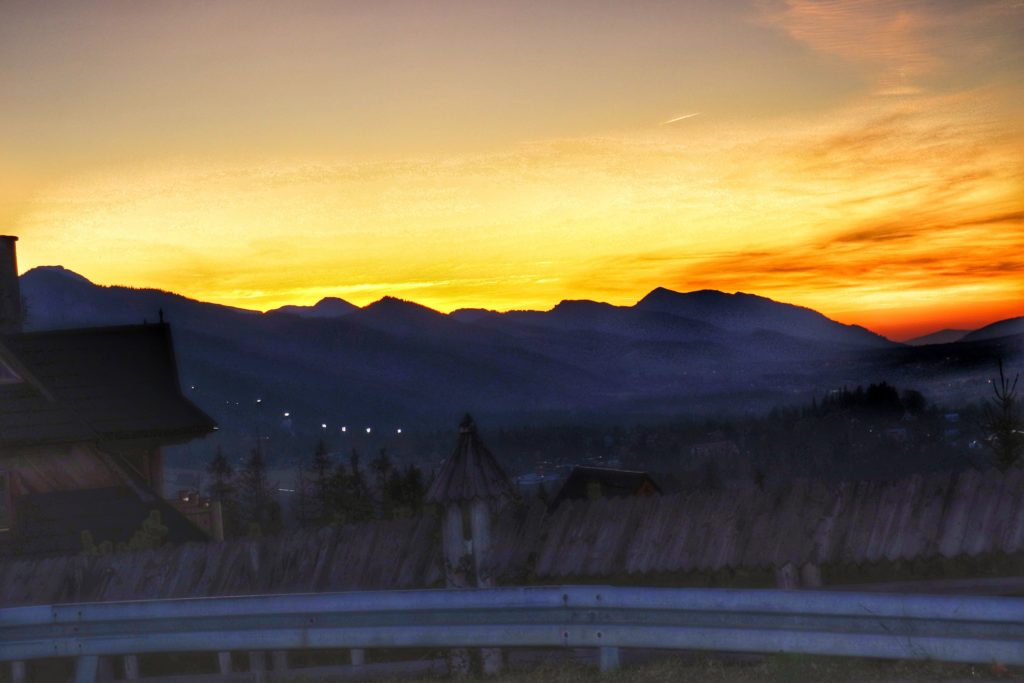 Cyrhla w mieście Zakopane, zachód słońca nad Tatrami, żółto pomarańczowe niebo, budynki