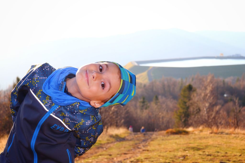Uśmiechnięte dziecko na tle zbiornika Żar widocznego ze szczytu Kiczera