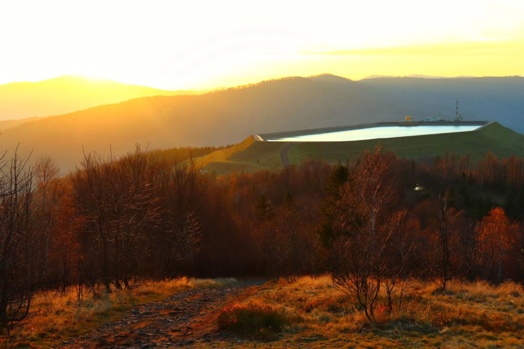 Zbiornik retencyjny na Górze Żar widozny ze szczytu Kiczera w Beskidzie Małym, jesienne drzewa oświetlone przez zachodzące słońce