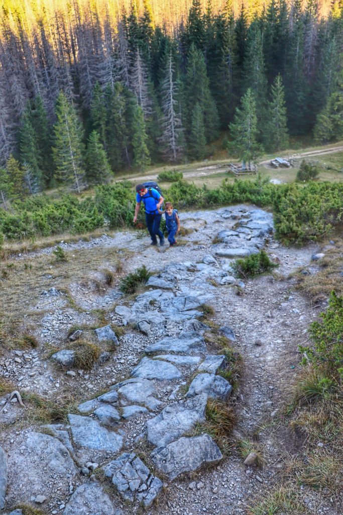 dwójka turystów, w tym dziecko idąy stromo w górę skalnym podejściem prowadzącym z Polany Kopieniec na szczyt Wielki Kopieniec