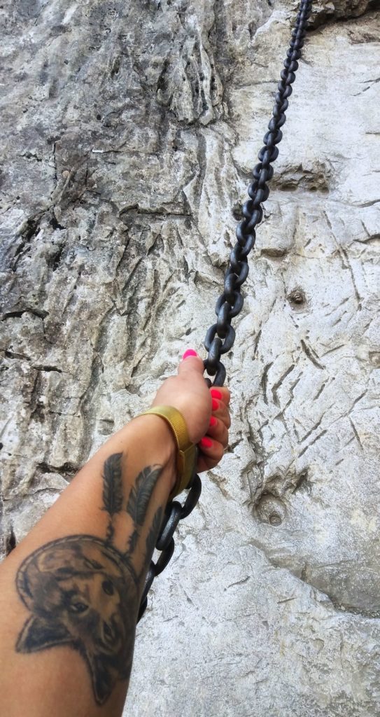 ręka kobiety trzymająca ułatwienie w postaci łańcucha na szlaku