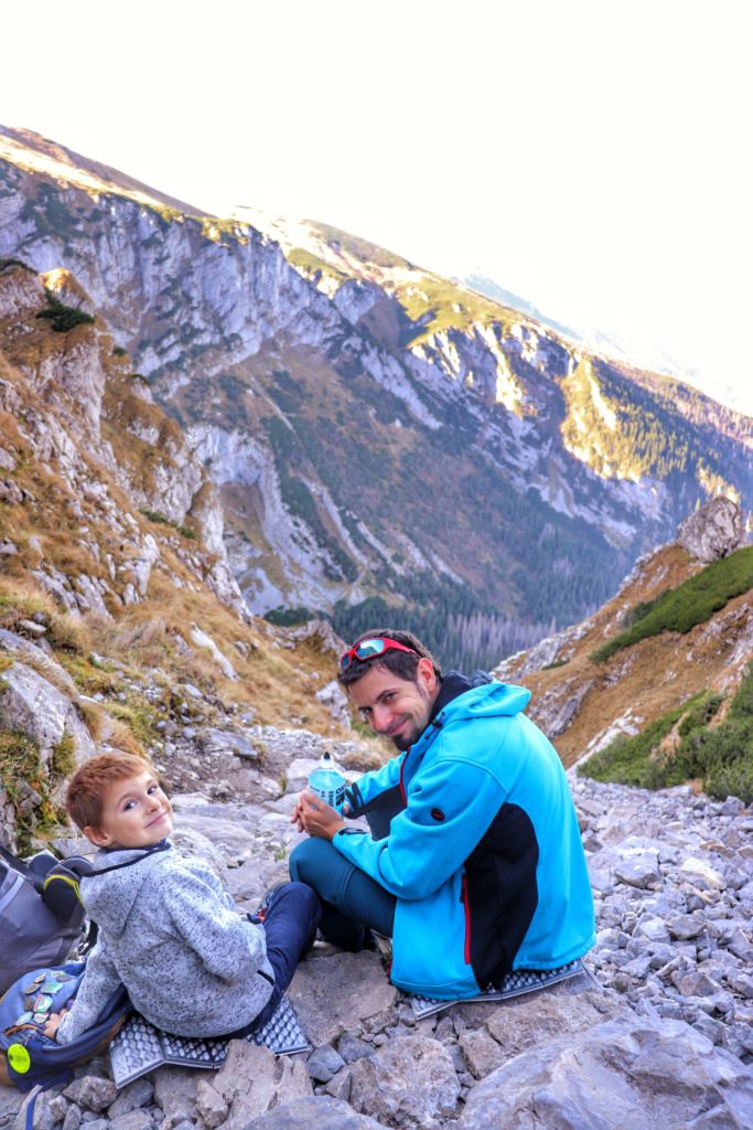 uśmiechnięty mężczyzna oraz dziecko odpoczywający na skałach, w tle tatrzańskie krajobrazy