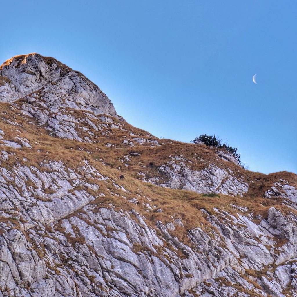 widok na wznoszące się nad Kobylarzowym Żlebem skały, niebieskie niebo i księżyc