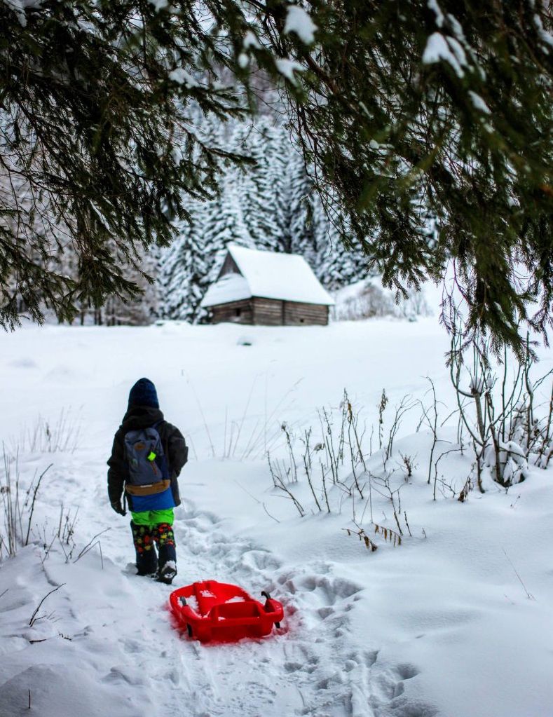 Dziecko ciągnące czerwone sanki, Polana Olczyska zimą (Tatry), drewniany szałas pasterski