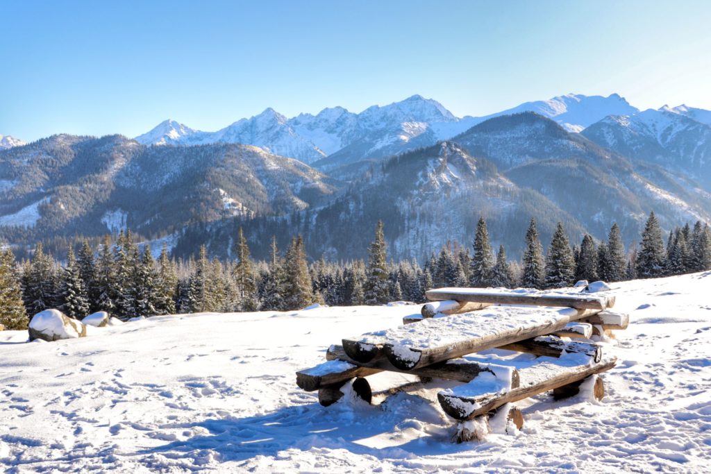 zima na Polanie Rusinowej, zaśnieżony stół z drewnianymi ławkami, w tle piękne szczyty Tatr pokryte śniegiem