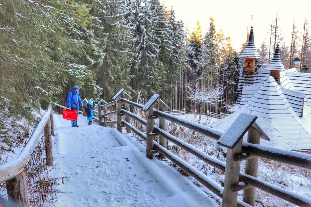 Mężczyzna z dzieckiem podziwiający budynek Sanktuarium na Wiktorówkach, niebieski szlak, zaśnieżone schody oraz ścieżka
