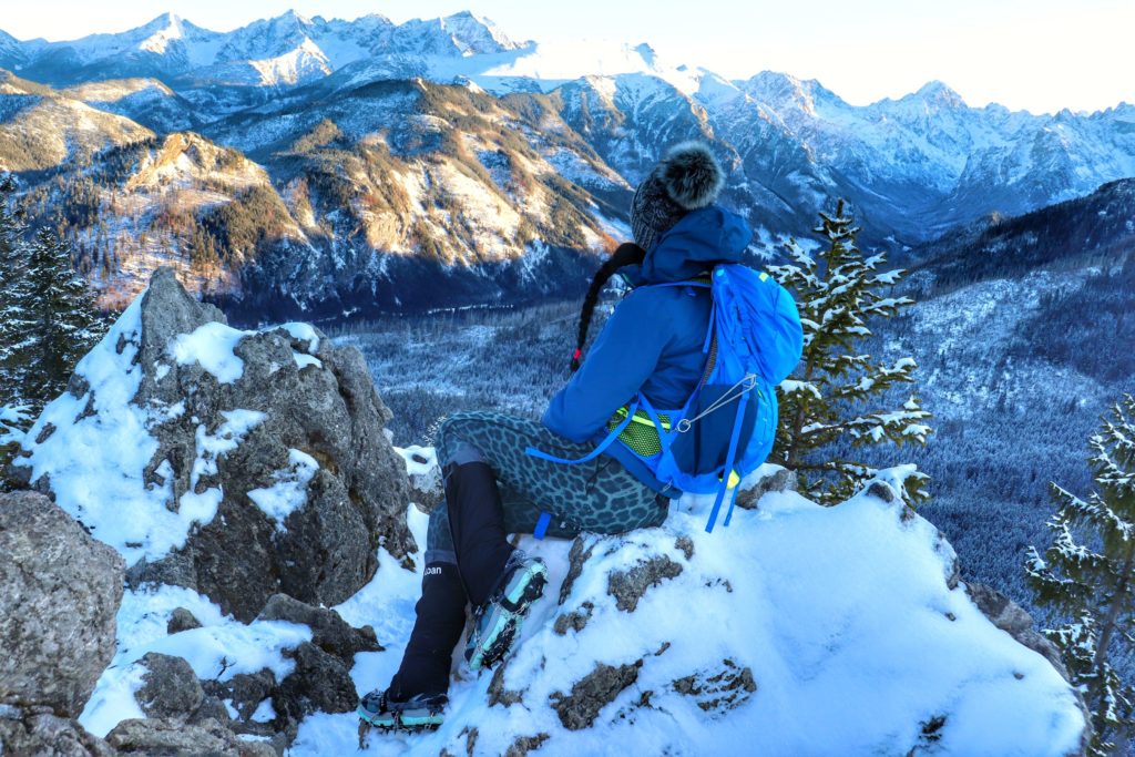 Turystka siedząca na skałach na Gęsiej Szyi, podziwiająca zaśnieżone tatrzańskie szczyty