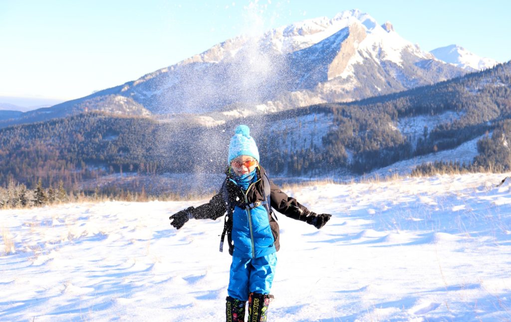 Zimowa Rusinowa Polana, na której znajduje się dziecko rzucające w górę śniegiem