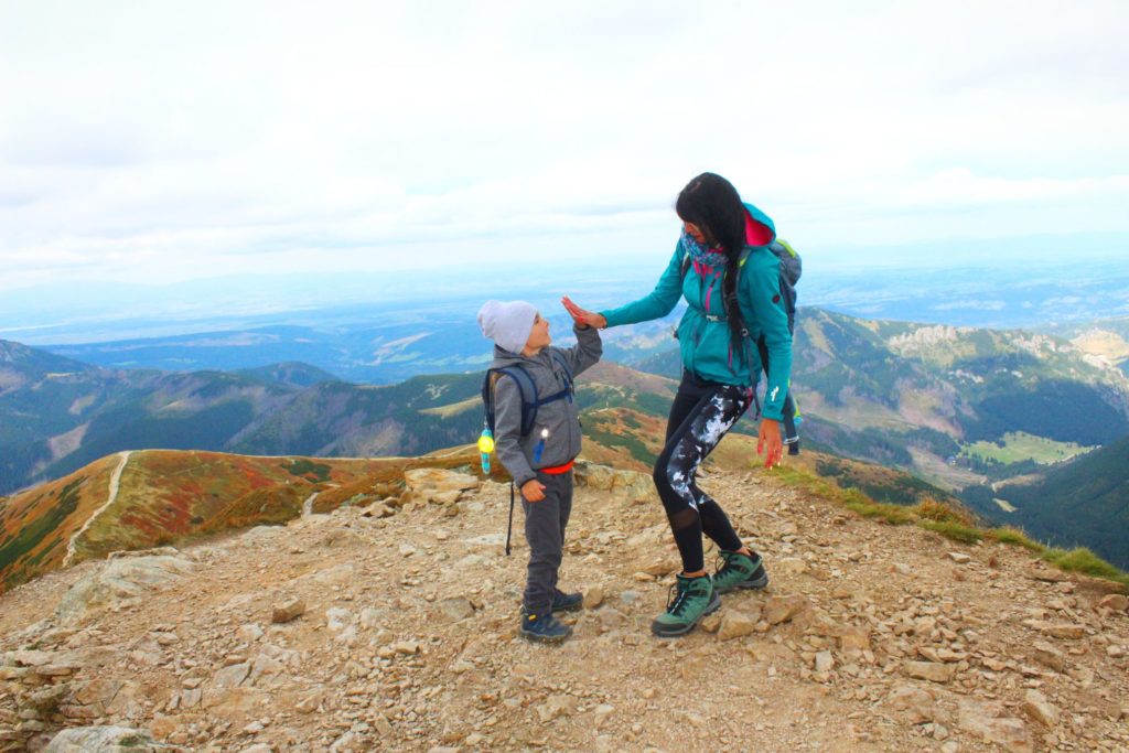 Dziecko przybija mamie piątkę na Wołowcu, w oddali widoczne krajobrazy górskie