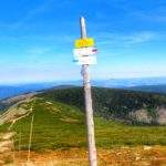 Słup z drogowskazami, żółta tabliczka Droga Jubileuszowa, krajobraz górski