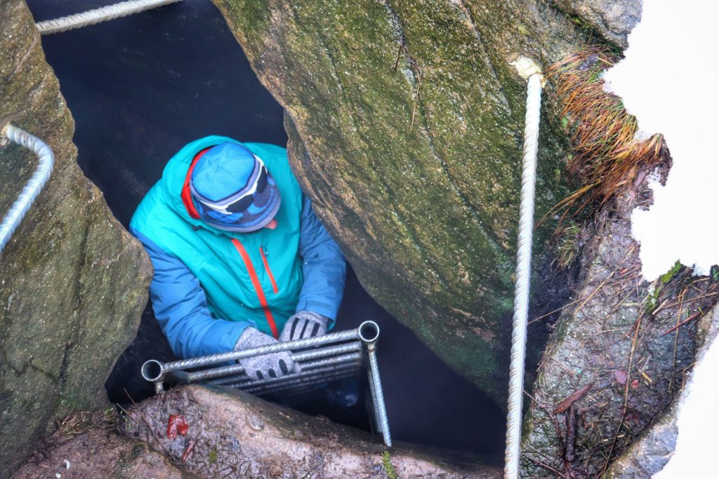 Turysta stojący na metalowej drabinie w Jaskini Malinowskiej