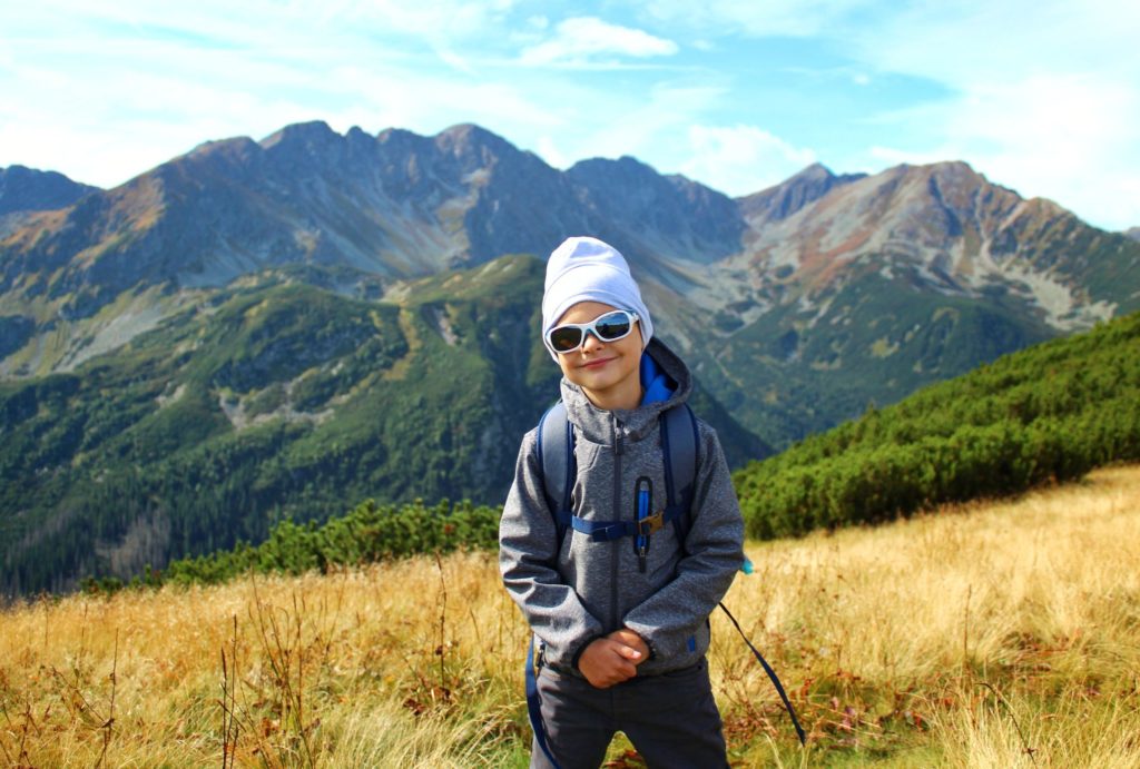 Uśmiechnięte dziecko stojące na tle Tatr Wysokich w okolicach szczytu Rakoń