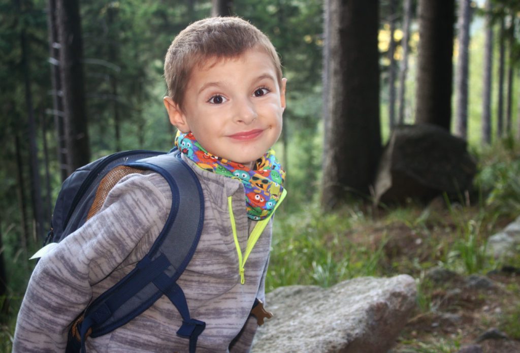 Uśmiechnięte dziecko odpoczywający na skale w lesie