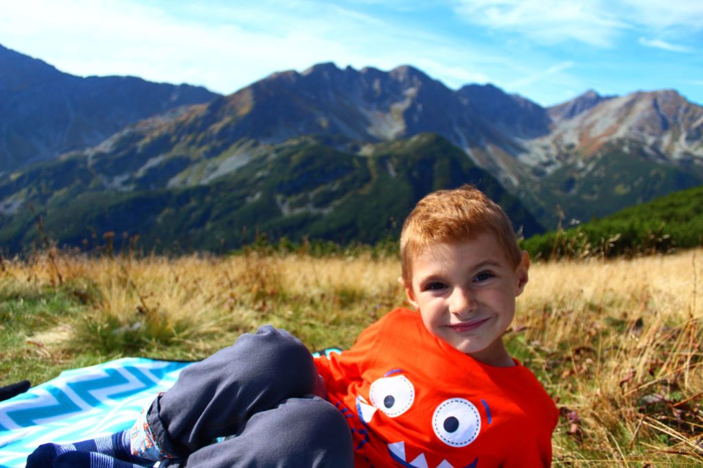 Zabratowa Przełęcz, odpoczywające na kocu piknikowym uśmiechnięte dziecko ciepły dzień, w tle Tatry,
