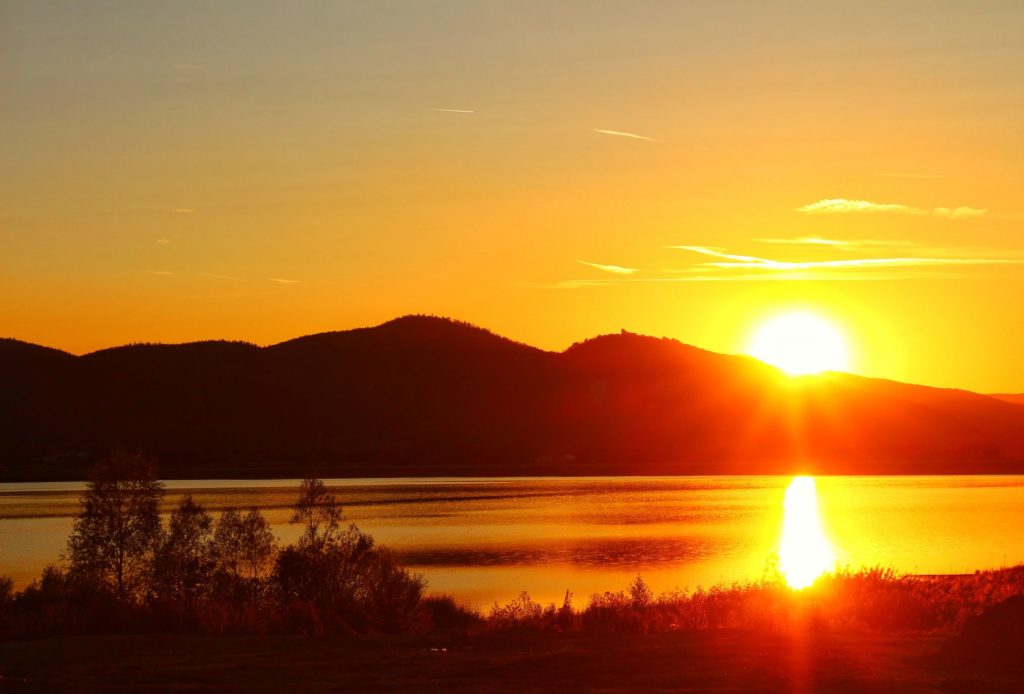 Zjawiskowy zachód słońca nad jeziorem, w tle Góry Izerskie, żółto - pomarańczowe niebo