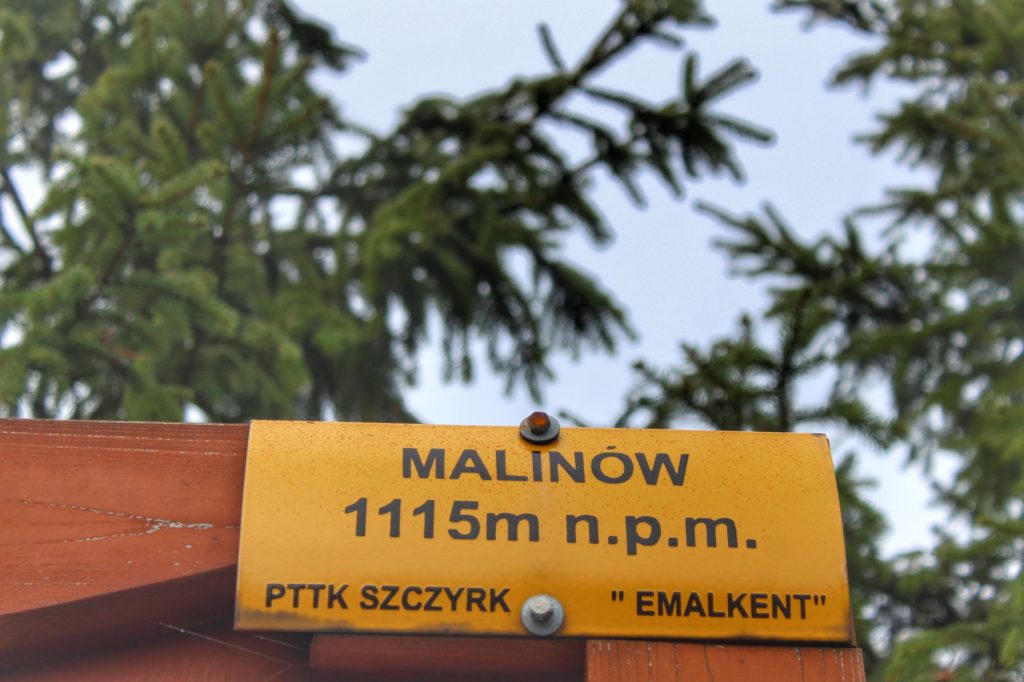 Żółta tabliczka PTTK Szczyrk z napisem Malinów 1115 metrów nad poziomem morza