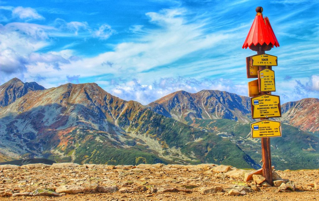 Szczyt Rakoń, słup z opisem szlaków, w tle widok na piękne tatrzańskie szczyty