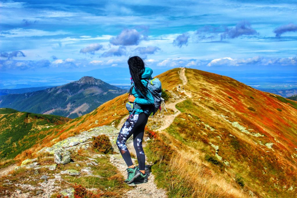 Turystka stojąca w Tatrach - okolice szczytu Rakoń, jesienne kolory, w oddali tatrzańskie szczyty