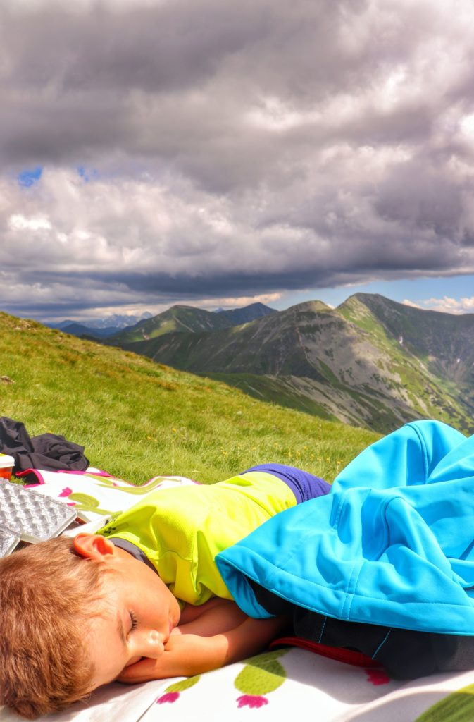 Dziecko słodko śpiące na kocu na Wołowcu, w oddali widoczne tatrzańskie szczyty