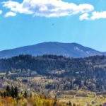 Paralotniarz lecący nad Beskidami, krajobraz górski wiosenną porą widziany z polany leżącej pod szczytem Jastrzębica