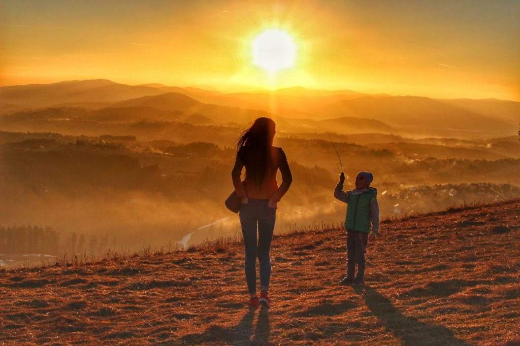 Zachód słońca na szczycie Ochodzita, dziecko z mamą podziwiają zachodzące słońce, żółtopomarańczowe niebo, krajobraz górski