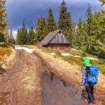 Drewniany szałas pasterski na Hali Cudzichowej, dziecko bawiące się w kałuży w pobliżu szałasu, szeroka droga
