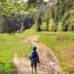 Dziecko wchodzące na polanę w Beskidzie Wyspowym, w oddali widać domek oraz las