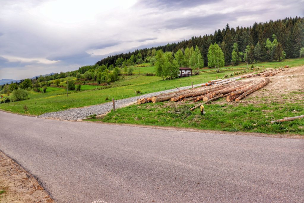Główna droga w miejscowości Chyszówka, zielony szlak na Mogielicę, wiosenne pola, pocięte drewno, zachmurzone niebo