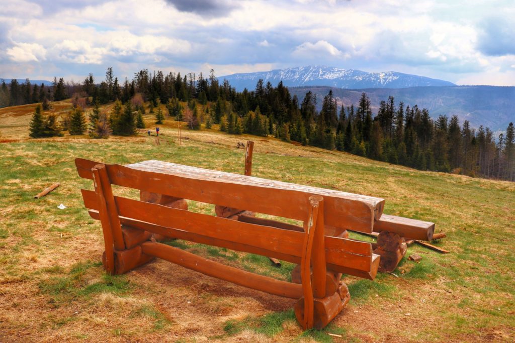 Lachów Groń, drewniane ławki ze stołem na polanie, widok na ośnieżone pasmo Babiej Góry, pochmurny dzień