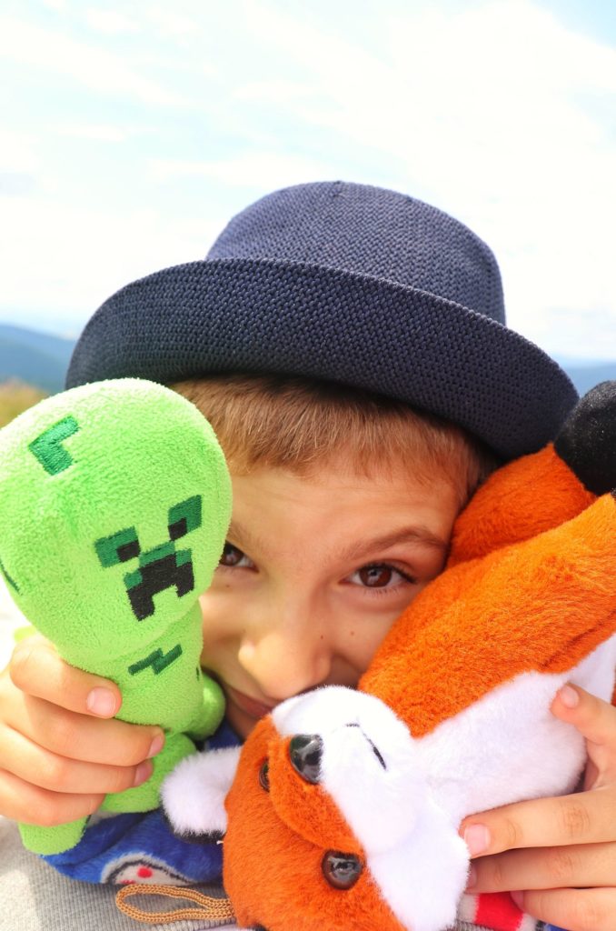 Szczęśliwe dziecko w kapeluszu z pluszowymi zabawkami