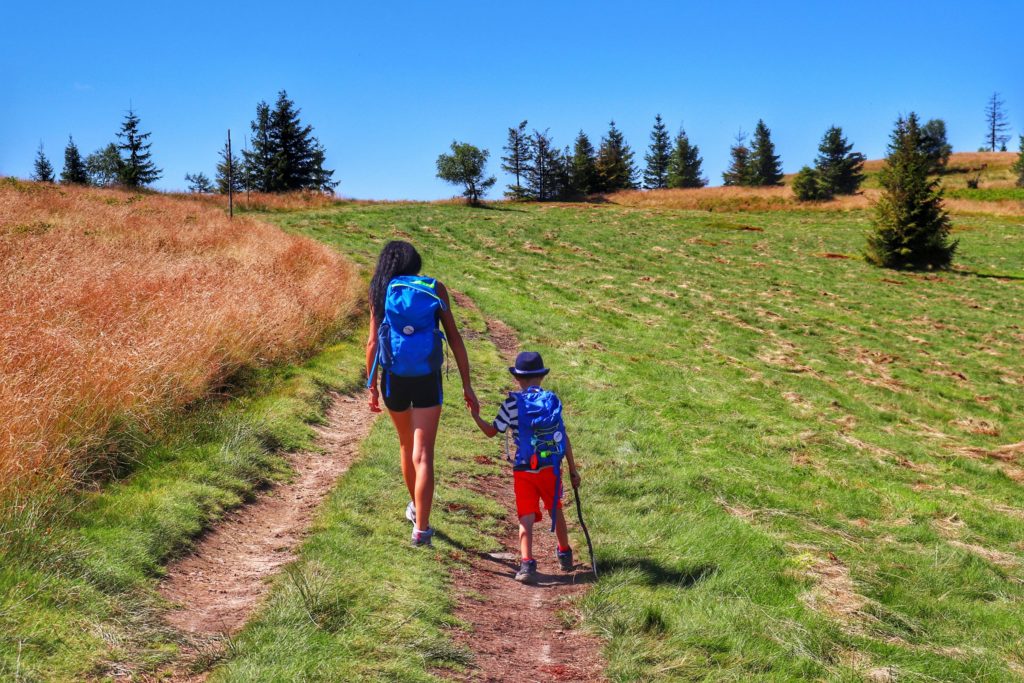 Turystka idąca z dzieckiem w górę polany na szczyt Lachów Groń