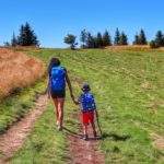 Turystka idąca z dzieckiem w górę polany na szczyt Lachów Groń