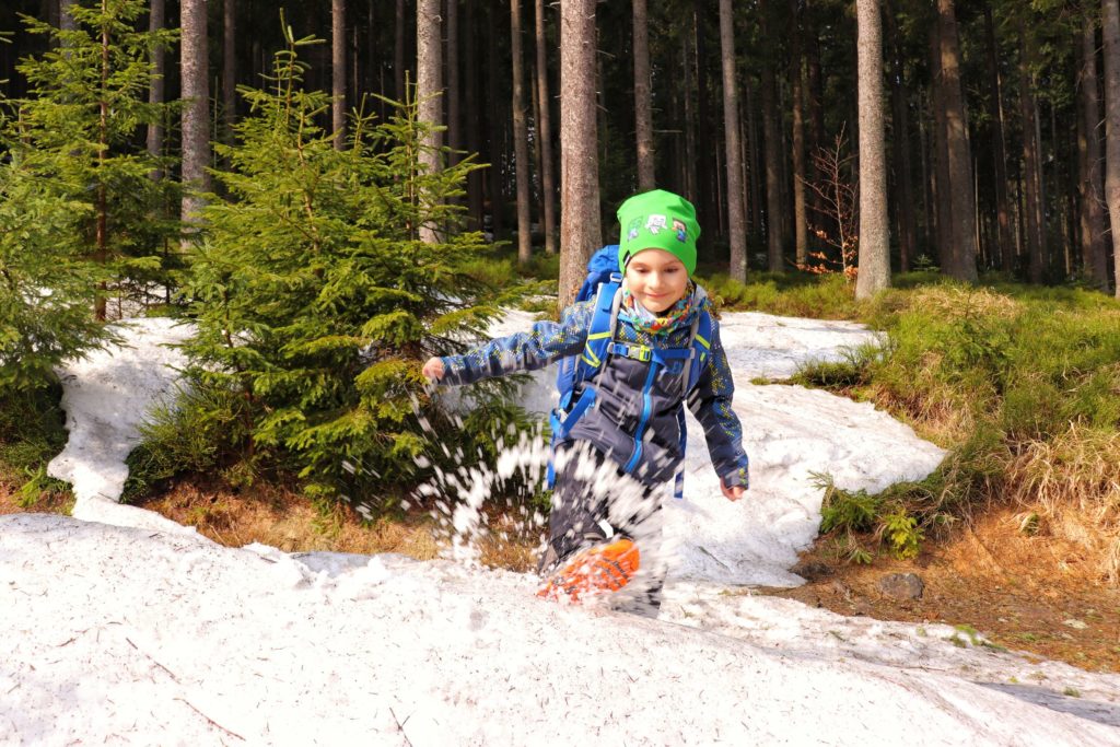 Uśmiechnięte dziecko bawiące się w śniegu na piękne,leśnej ścieżce