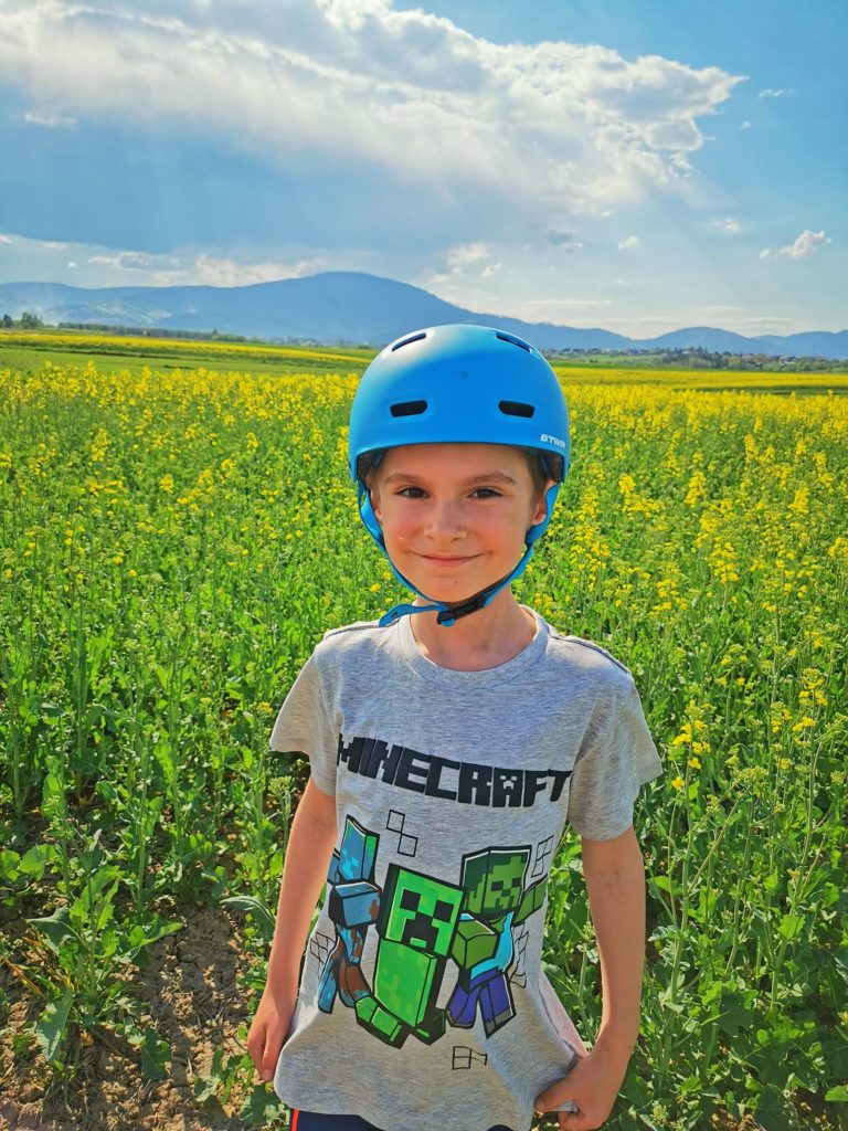 Uśmiechnięty chłopiec, żółte pole rzepakowe, w tle szczyt Skrzyczne (Beskid Żywiecki)