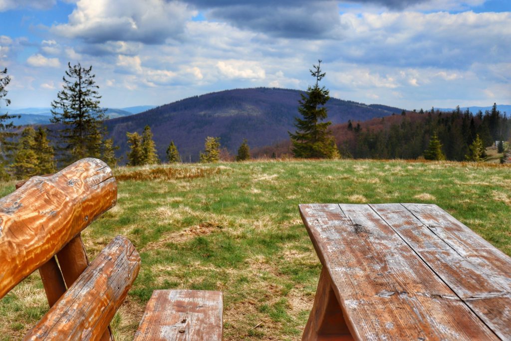 Widok na szczyt Jałowiec ze szczytu Lachów Groń, drewniana ławka i stół