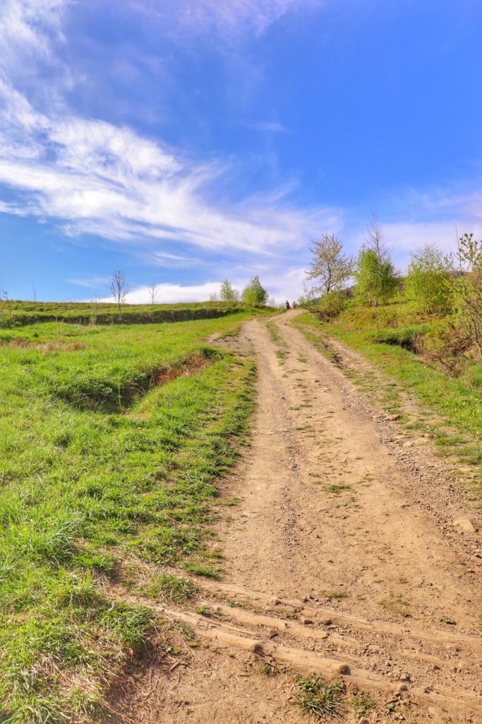 Ścieżka prowadząca między polami,wiosenny dzień, niebieskie niebo