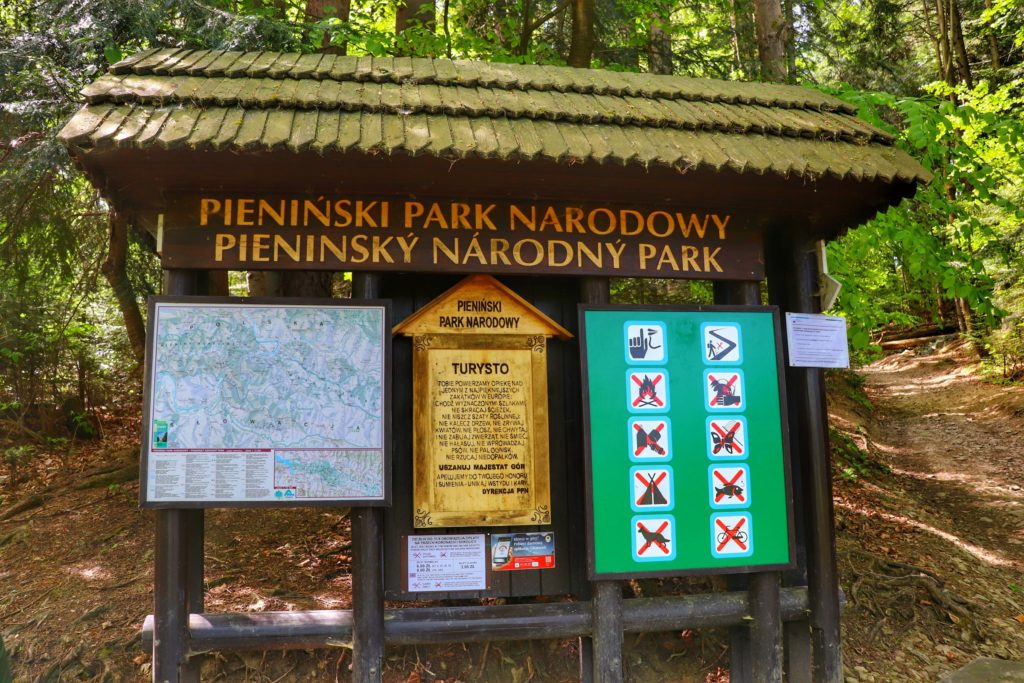 Drewniana tablica w Pienińskim Parku Narodowym z mapą, przydatnymi informacjami dla turystów, cennikiem biletów