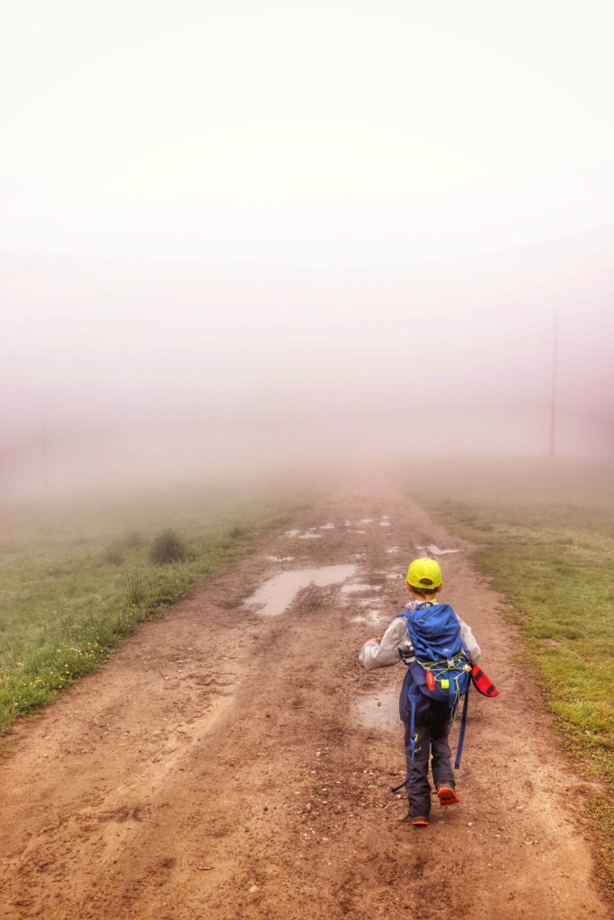 Dziecko na szerokiej, prostej drodze prowadzącej od Rancza Błatnia do schroniska na Błatniej, mgła, kałuże