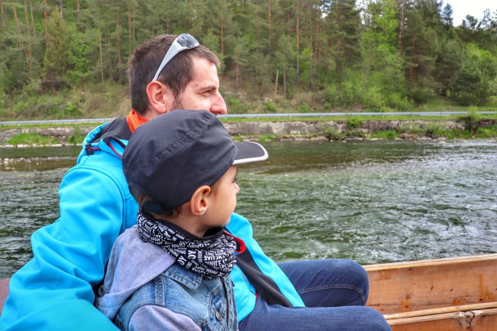 Mężczyzna z dzieckiem na drewnianej tratwie podczas spływu przełomem Dunajca w Pieninach