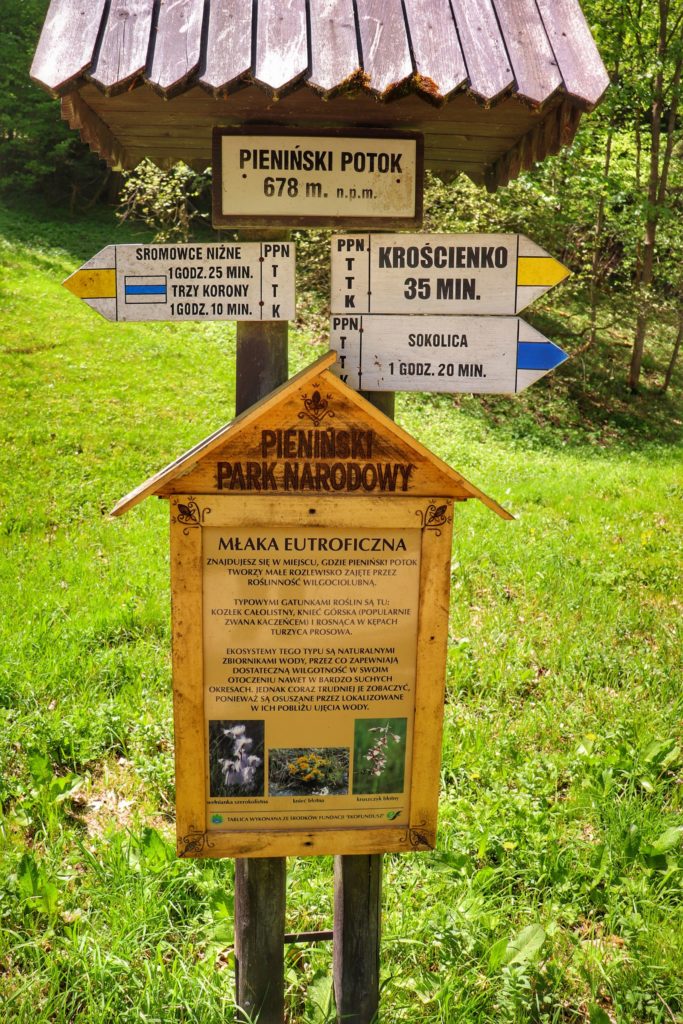 Tabliczka z napisem Pieniński Potok, opis drogowskazów - żółtego i niebieskiego, drewniana tablica Pienińskiego Parku Narodowego