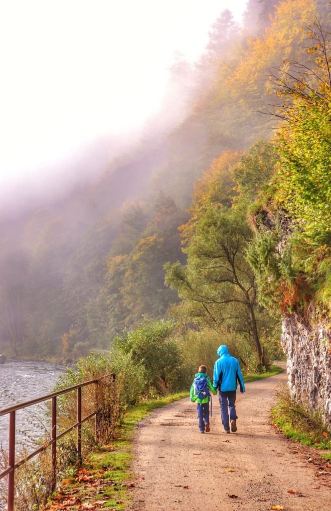 Turysta z dzieckiem idący wzdłuż Dunajca na zielonym szlaku na Sokolicę w Pieninach, jesienny krajobraz