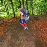 Mężczyzna schodzący stromo w dół, leśną ścieżką w kierunku Źródełka Maryjnego na czerowno - żółtym szlaku na Hrobaczą Łąkę