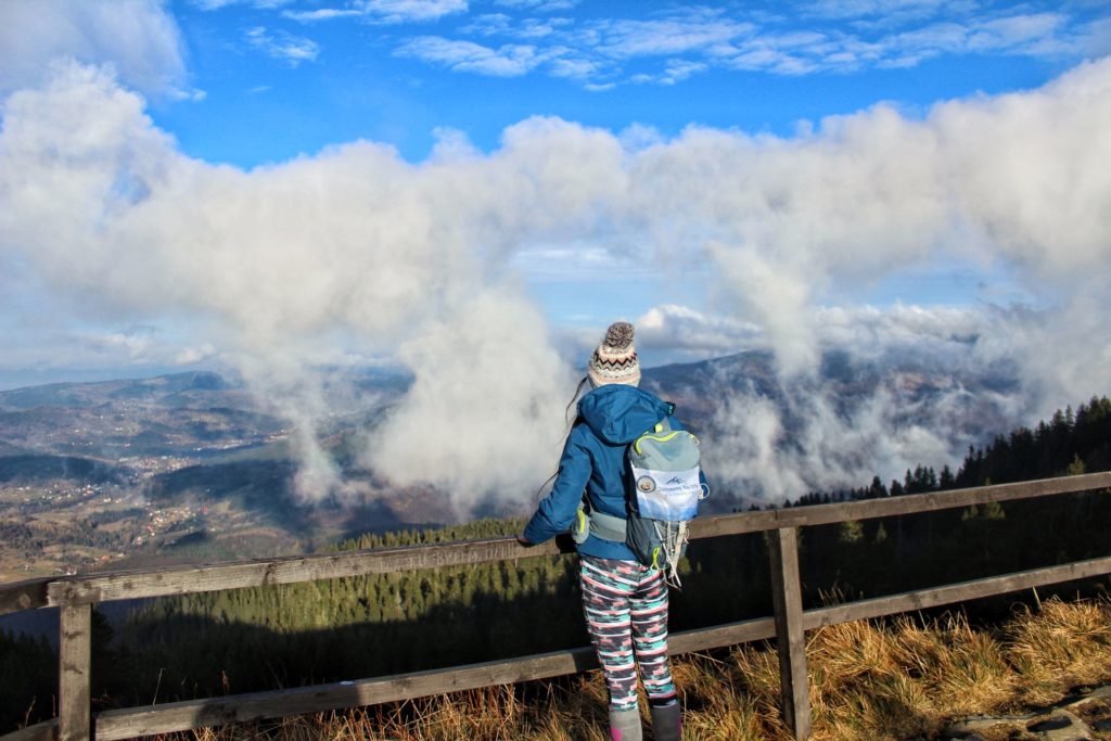 Turystka stojąca na tarasie widokowym - Przełęcz Brona, piękne niebieskie niebo, krajobraz górski wyłaniający się zza chmur